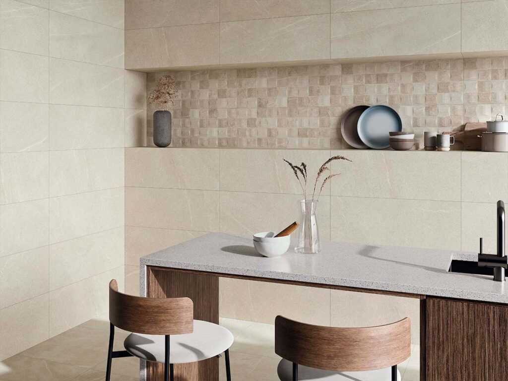 Pared de cocina moderna revestida con cerámica Bellevue Ivory efecto piedra, combinando baldosas grandes con un mosaico a juego en la zona del salpicadero.