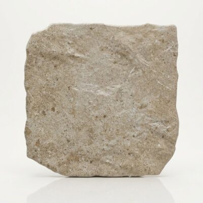 Baldosa de porcelánico beige con textura de piedra rústica y bordes irregulares.