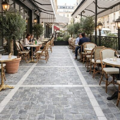 Suelo de porcelánico imitación piedra gris country en una terraza de cafetería con mesas.