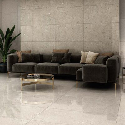 Salón moderno con suelo y pared principal revestidos con azulejo Caliope Beige brillante, un elegante efecto piedra en tono beige con sutiles inclusiones y reflejos.
