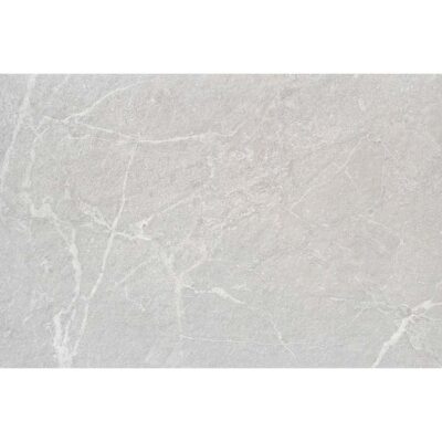 Pared de un baño luminoso revestida con azulejos Malek Pearl, que aportan una textura de efecto piedra en un elegante tono perla.