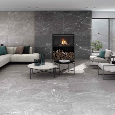 Salón moderno con suelo y pared de chimenea revestidos con azulejo porcelánico Malek Black, efecto piedra oscura con vetas blancas.