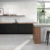 Ambiente de cocina moderna con suelo y pared revestidos con la baldosa cerámica Caliope Pearl, que aporta una luminosa textura de efecto piedra.