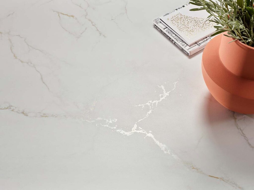 Detalle de una superficie revestida con el porcelánico Thuile Venato Natural, mostrando de cerca su efecto de mármol blanco con vetas doradas y grises.