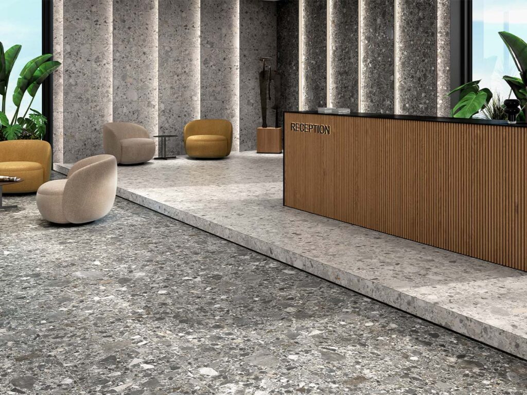Suelo porcelánico efecto piedra, modelo Inlay, en una combinación de tonos perla y grafito, instalado en una moderna zona de recepción con paredes revestidas a juego.