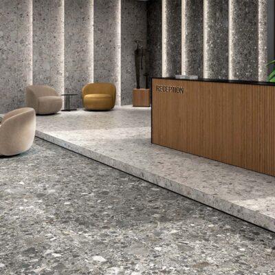 Suelo porcelánico efecto piedra, modelo Inlay, en una combinación de tonos perla y grafito, instalado en una moderna zona de recepción con paredes revestidas a juego.