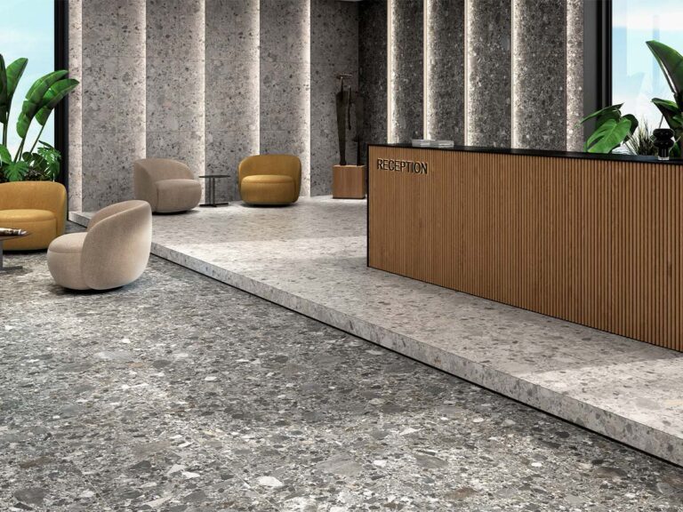 Suelo porcelánico efecto piedra, modelo Inlay, en una combinación de tonos perla y grafito, instalado en una moderna zona de recepción con paredes revestidas a juego.