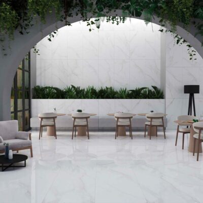 Ambiente de una cafetería de lujo con un suelo brillante de efecto mármol Lumiere White, cuyas baldosas pulidas también revisten las paredes creando un espacio luminoso y continuo.