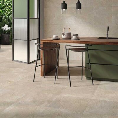 azulejo porcelánico triunfo natural en cocina moderna con isla verde oliva, encimera de madera, taburetes de diseño y zona de terraza exterior integrada