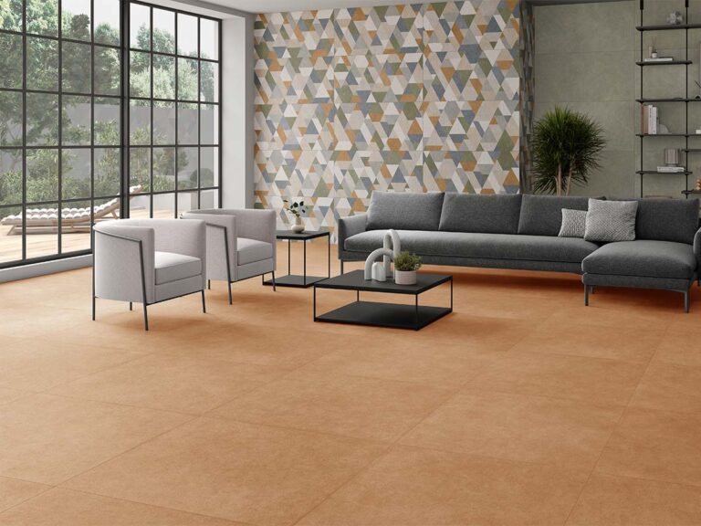 Suelo efecto cemento modelo Pursue Terre, en un cálido tono tierra, ambientado en un salón moderno con grandes ventanales y una pared de acento con diseño geométrico.
