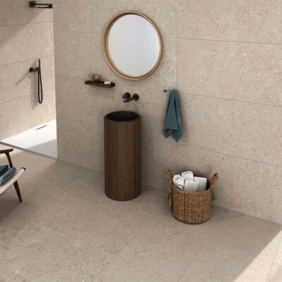 Baño moderno con suelo y paredes revestidos con baldosas Caliope Beige, efecto piedra en tono beige claro con sutiles inclusiones, y vistas a la ciudad.
