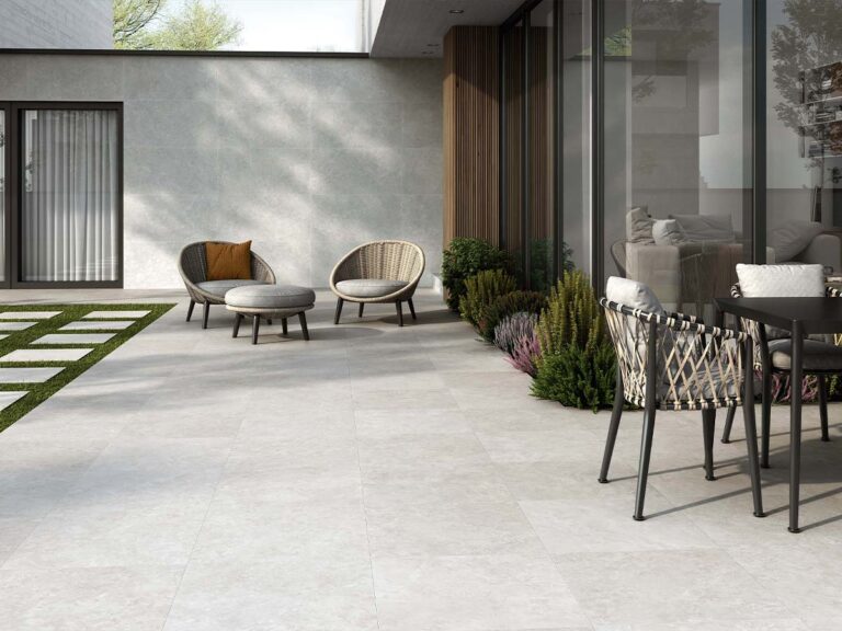 Patio exterior moderno pavimentado con el suelo porcelánico antideslizante Premiere Grey, que también reviste la pared para unificar el espacio.