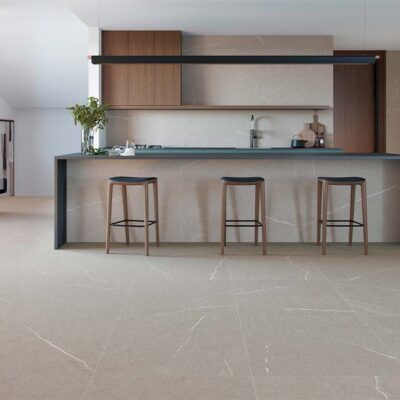 Suelo porcelánico Origins Grey efecto piedra con vetas blancas, instalado en el suelo y paredes de una cocina moderna con isla y muebles de madera