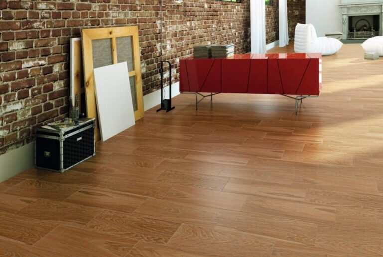 Salón moderno con suelo de baldosas de acacia miel, pared de ladrillo y mueble rojo.