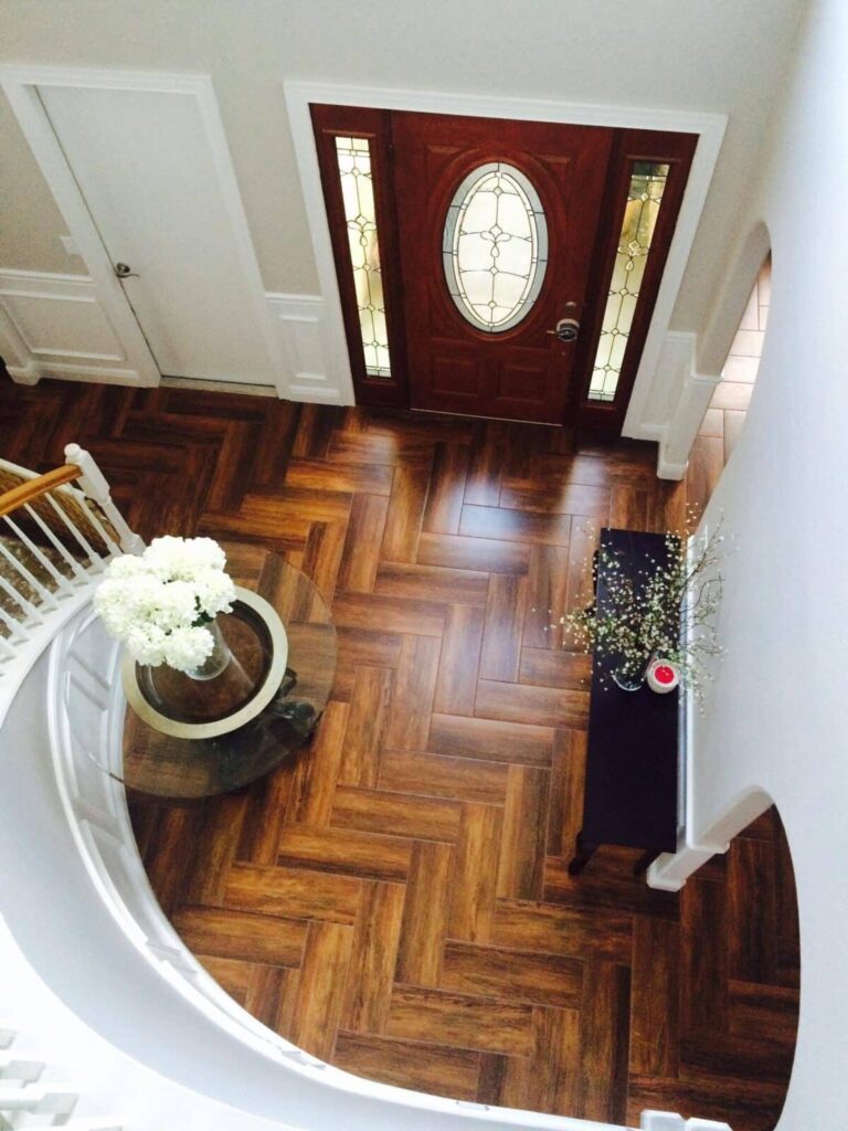 Foyer con suelo porcelánico imitación madera en patrón de espiga, junto