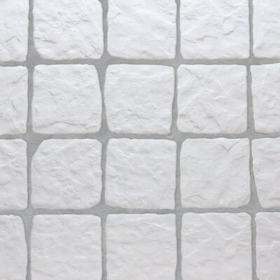 Baldosa porcelánica cuadrada con acabado que imita la piedra en tono blanco, ideal para revestimientos de interiores y exteriores.