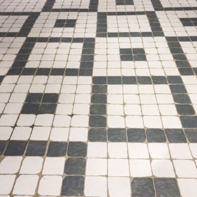 pavimento cerámico tipo mosaico con piezas cuadradas blancas y antracita formando patrón geométrico clásico