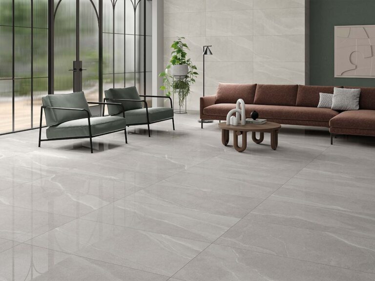 Amplio salón moderno con suelo y pared revestidos en azulejo cerámico Austral Pearl, efecto piedra en tono perla claro con sutiles vetas." Opción 2: "Elegante salón con pavimento y revestimiento de pared en azulejo cerámico Austral Pearl, mostrando su luminoso efecto piedra con un delicado veteado, junto a grandes ventanales.