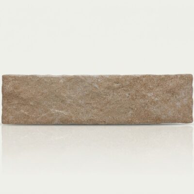 Baldosa rectangular de suelo porcelánico efecto piedra en tono beige claro, textura rugosa y reflejo en superficie brillante.