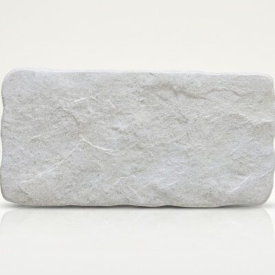 Azulejo porcelánico de color hueso con textura de piedra rústica.