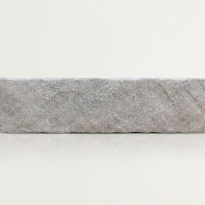 Azulejo porcelánico rectangular de imitación piedra country perla con textura rugosa.