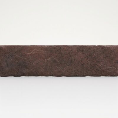 Azulejo rectangular de imitación piedra en tono granate rodeno sobre fondo blanco.