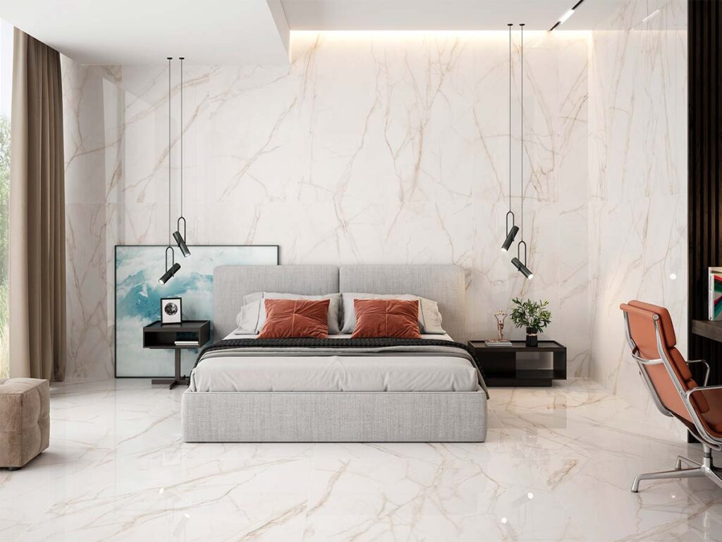 Ambiente de dormitorio de lujo con el suelo y la pared revestidos con azulejo porcelánico brillante Jolie Warm, que crea un efecto continuo de mármol blanco con vetas doradas.