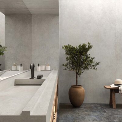 Pared de baño revestida con azulejo porcelánico Feroe Pearl, mostrando su textura de efecto cemento y su luminoso color perla.