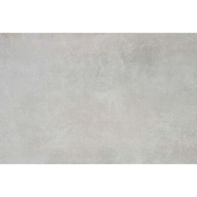 Baldosa porcelánica Comodo Grey con acabado pulido y efecto de cemento en tono gris, vista en perspectiva en un suelo.