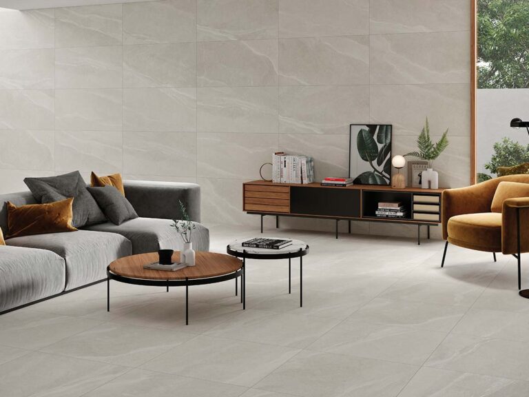 Salón moderno con suelo y pared revestidos con baldosa cerámica Austral Pearl, imitación piedra en un luminoso tono perla con sutiles vetas.