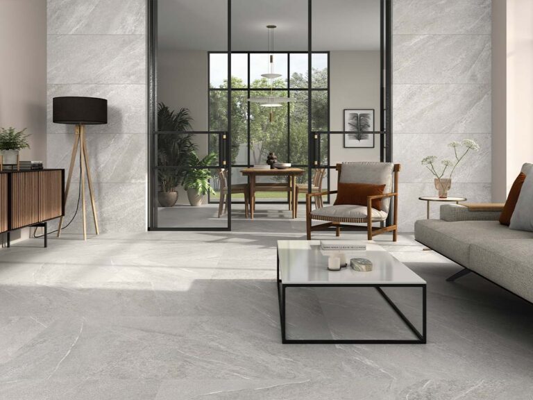 Salón moderno con suelo y paredes revestidos con baldosa Sakhir Grey, efecto piedra en tono gris claro con sutiles vetas blancas.