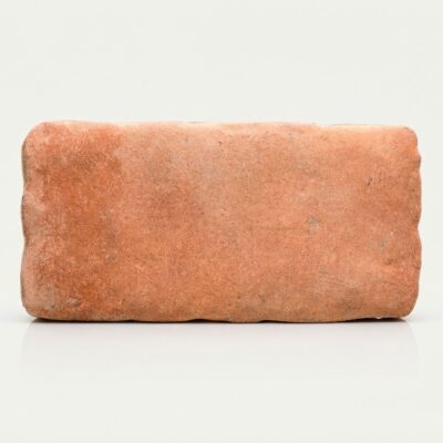 Baldosa porcelánica rectangular de color terracota con textura rugosa estilo cotto.