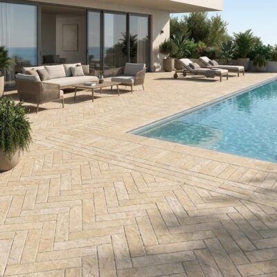 Suelo porcelánico imitación piedra en terraza de piscina con mobiliario exterior.