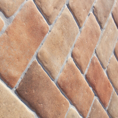 azulejo cerámico rectangular de imitación barro en tonos rojizos con bordes irregulares y textura mineral