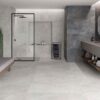 Vista del suelo de un baño moderno con baldosas cerámicas Feroe Pearl, de color perla claro, creando un ambiente luminoso.