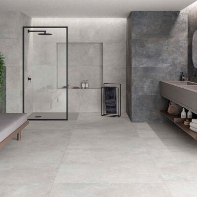 Vista del suelo de un baño moderno con baldosas cerámicas Feroe Pearl, de color perla claro, creando un ambiente luminoso.