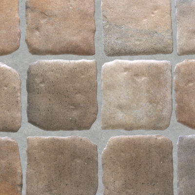 alt suelo de terraza exterior con azulejos cuadrados de imitación barro en tonos teja, dispuestos en filas horizontales con juntas de mortero gris