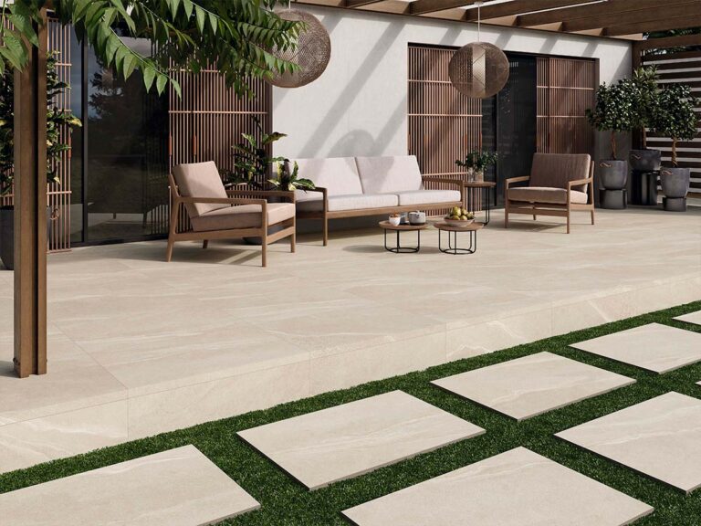 azulejo imitación piedra austral ivory en terraza con sofás, pérgola de madera y camino de baldosas sobre césped