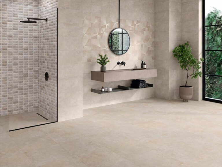 Suelo de un baño moderno pavimentado con porcelánico antideslizante Feroe Greige, que sirve de base neutra para las paredes decorativas con mosaicos y patrones geométricos.