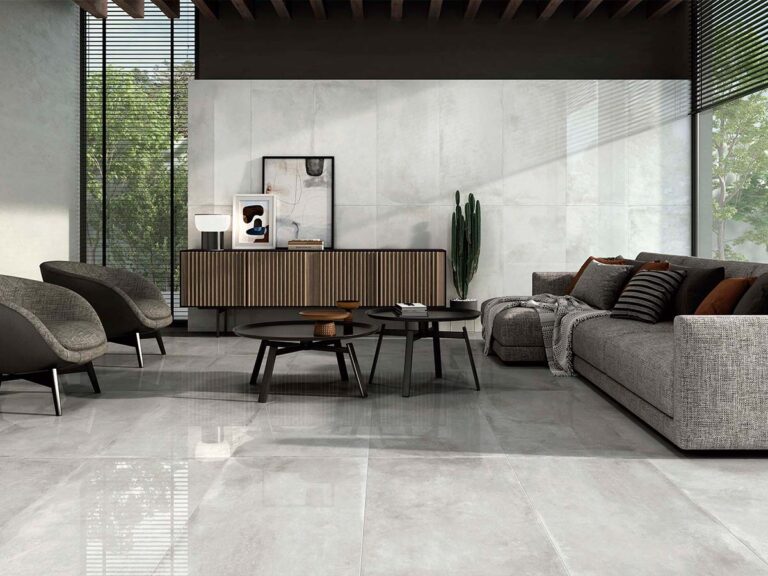 Suelo porcelánico con efecto de cemento pulido, modelo Comodo Pearl, en un tono gris perla muy claro, instalado en una estancia luminosa.