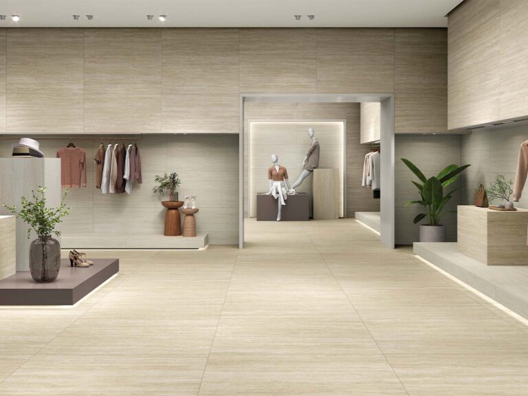 Ambiente de una boutique de moda con el suelo y las paredes revestidos con el porcelánico Fortune Natural, que aporta una textura elegante de mármol travertino beige.
