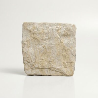 Un azulejo de suelo porcelánico rústico con textura de piedra en tonos beige.
