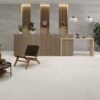 Suelo porcelánico moderno Austral Pearl, en tono perla claro con sutiles vetas, instalado en una amplia zona de recepción con paredes grises a contraste y mostrador de madera.