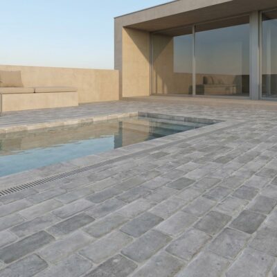 El suelo porcelánico Benisa Gris rodea una piscina moderna con zona de descanso. Cerámicos es.