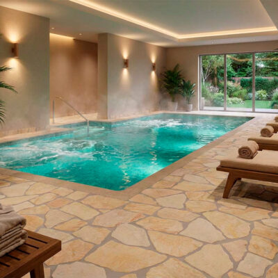Se observa una piscina interior con estilo relajante, suelo de piedra natural de tono beige, formato irregular y acabado mate.