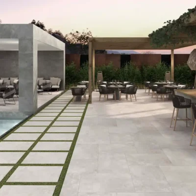 suelo porcelánico exterior efecto cemento gris en terraza con piscina, zona chill out y bar al aire libre con mobiliario moderno
