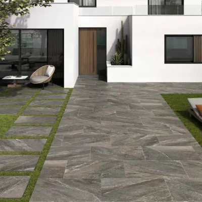 suelo exterior con baldosa porcelánica imitación piedra natural en jardín moderno con zonas verdes y camino de acceso