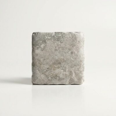 Baldosa de suelo porcelánico efecto piedra natural en color gris claro, textura rugosa.