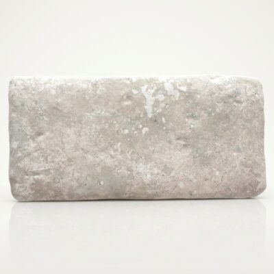 Un espacio interior minimalista con suelo de piedra de tono gris claro, acabado rugoso y formato rectangular.