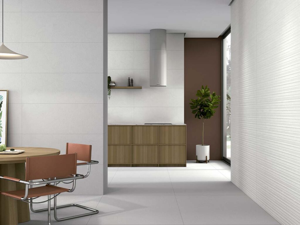 Cocina comedor con suelo porcelánico blanco mate y revestimiento cerámico blanco en relieve tipo rayado, ideal para espacios interiores modernos.